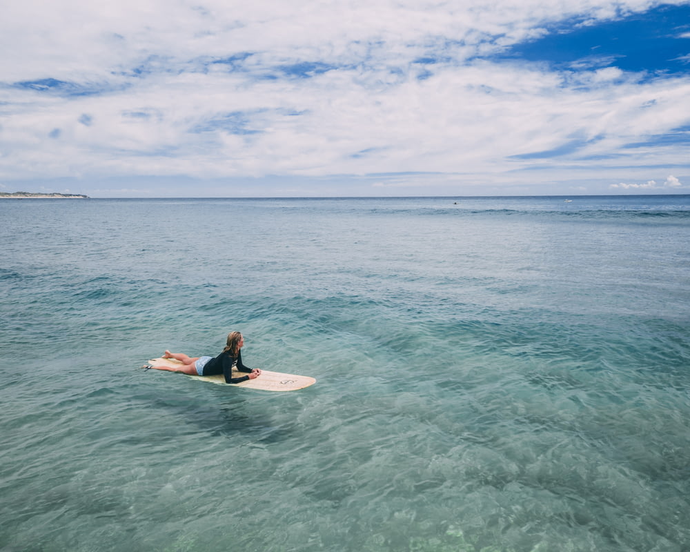 woman lying on surfboard