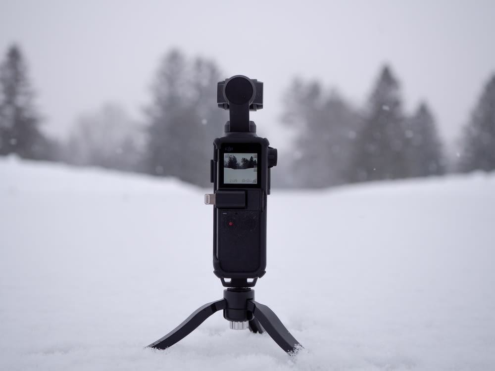 black camera with stand on snow field