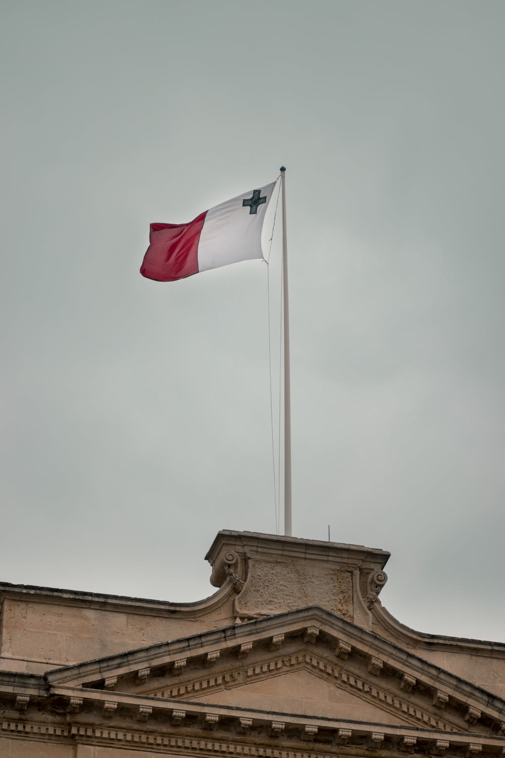 white and red flag under grey clouds