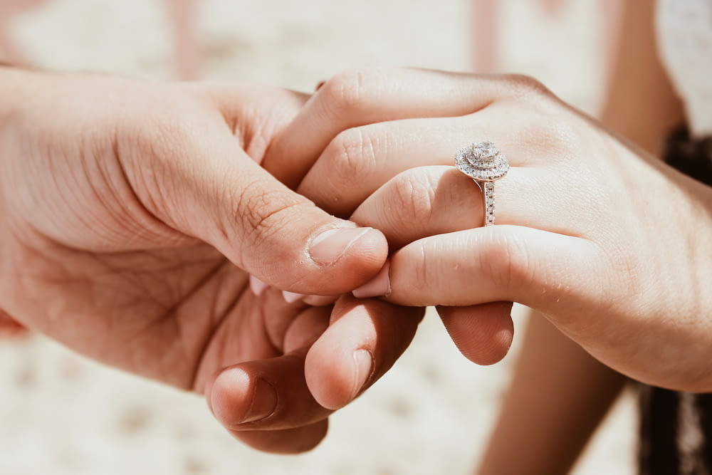 persona que sostiene la mano de otra persona con un anillo