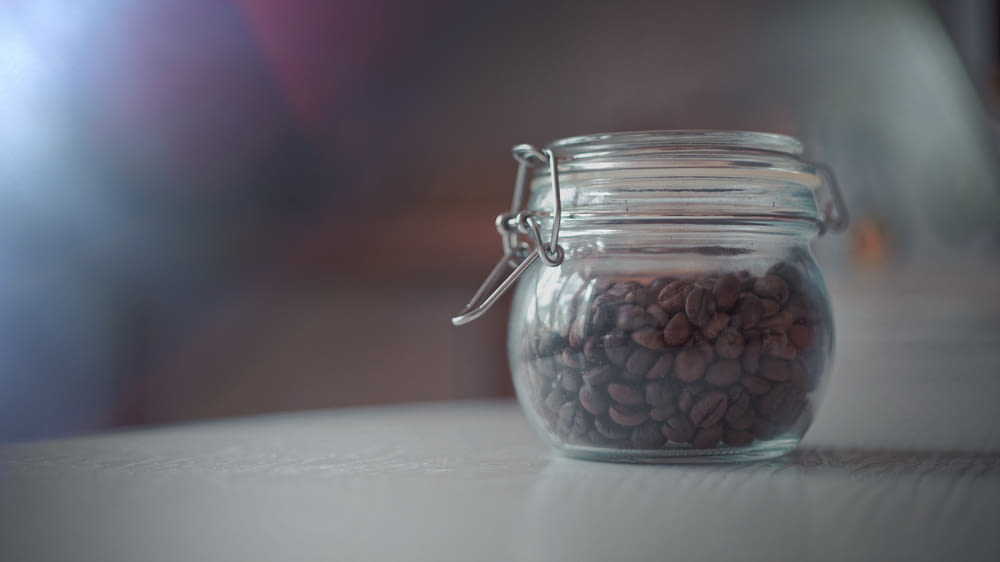 clear glass coffee jar with coffee beans