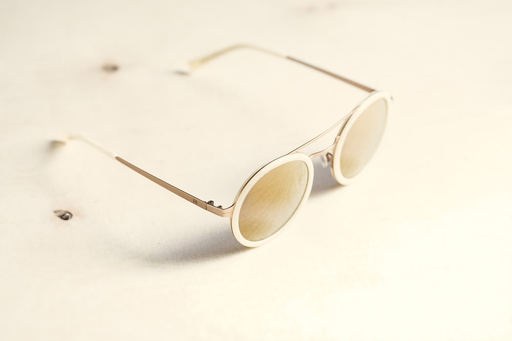 óculos de sol de lente marrom na superfície branca
