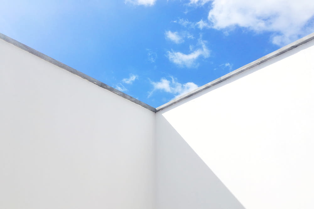 white painted wall under blue and white skies