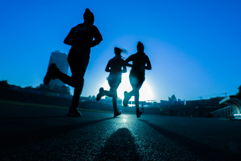 Silueta de tres mujeres corriendo en carretera de hormigón gris