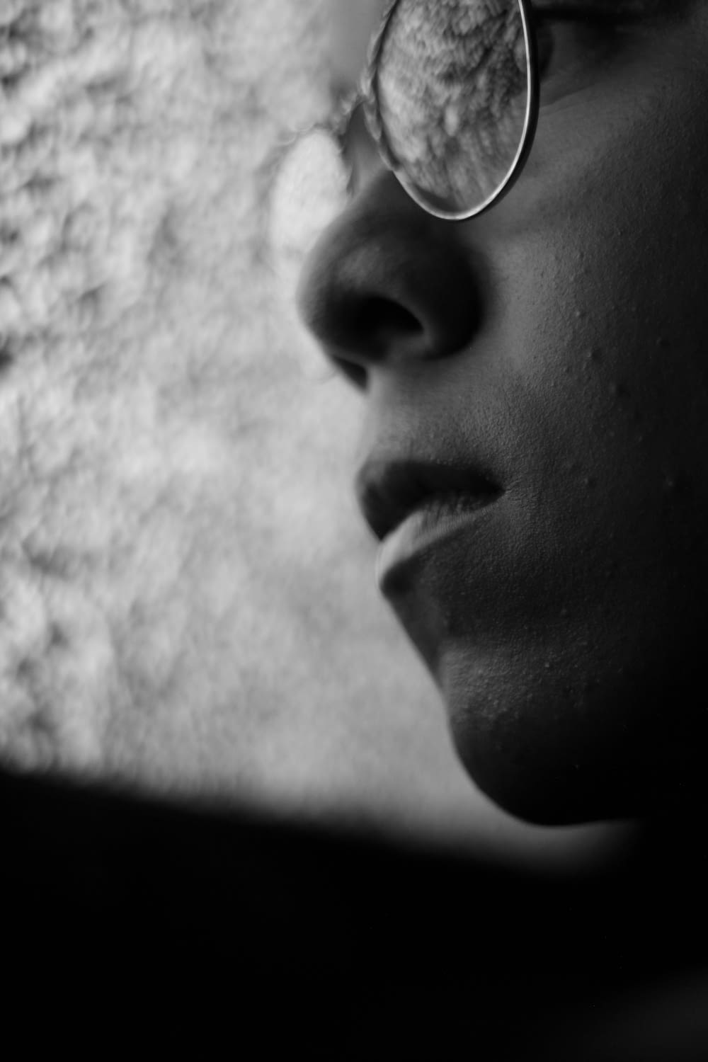 grayscale photo of person wearing eyeglasses looking at glass