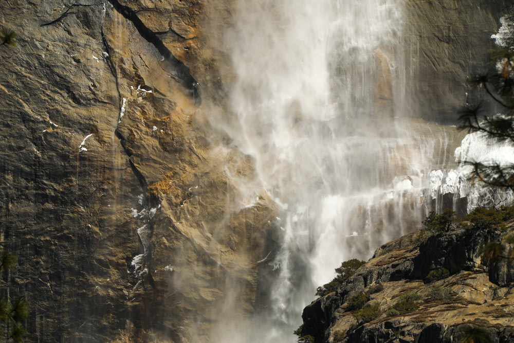 Fotografia time-lapse dell'acqua che cade dalla caduta d'acqua sulle rocce durante il giorno