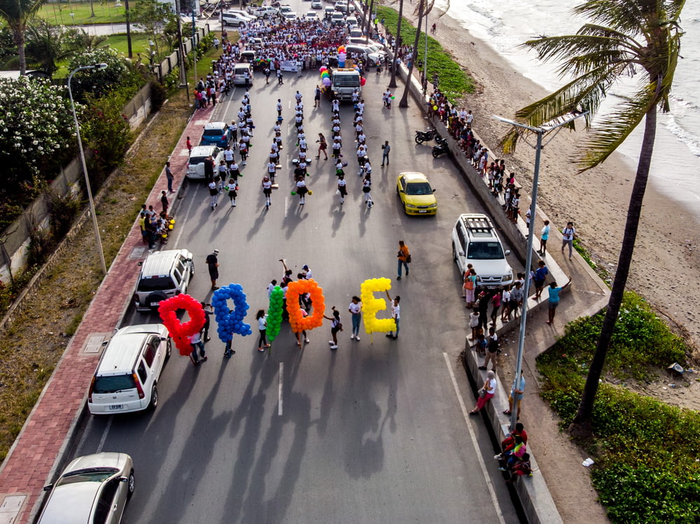grupo de pessoas caminhando na estrada carregando balões Pride