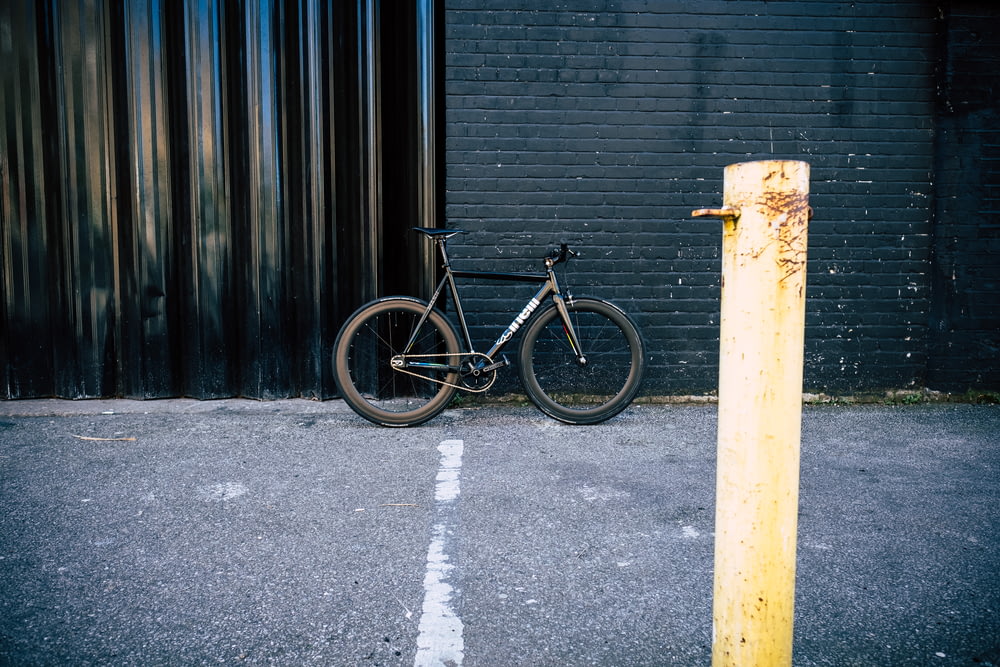 black mountain bike parked beside wall