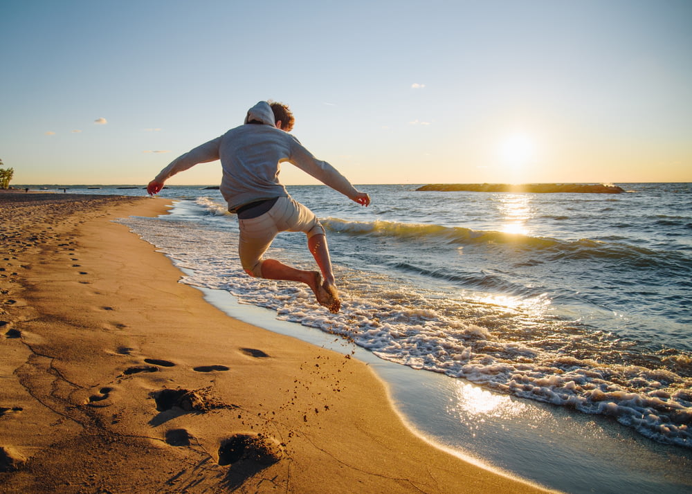 man jumping at the beach during golden hour