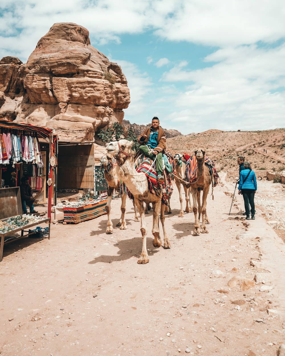 man riding camel near brown rock formation