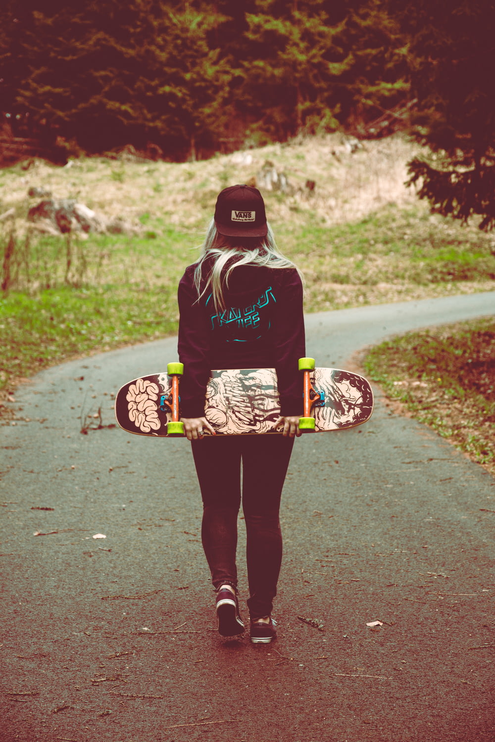 woman carrying skateboard walking on pathway