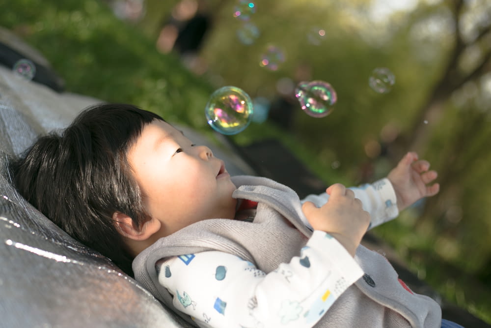 a little boy laying on top of a blanket next to bubbles