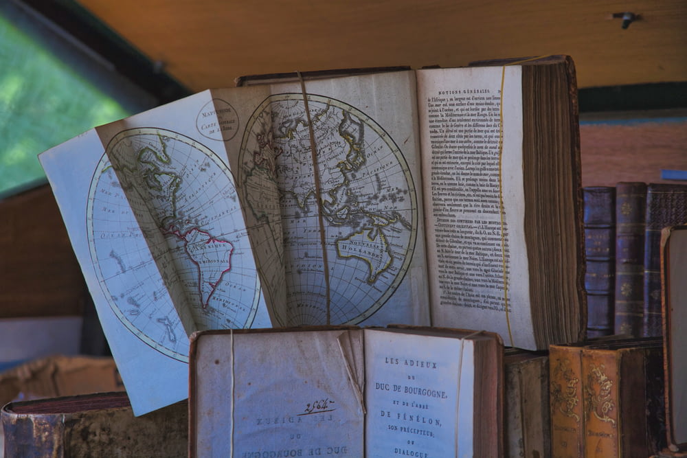 a stack of old books with maps on them