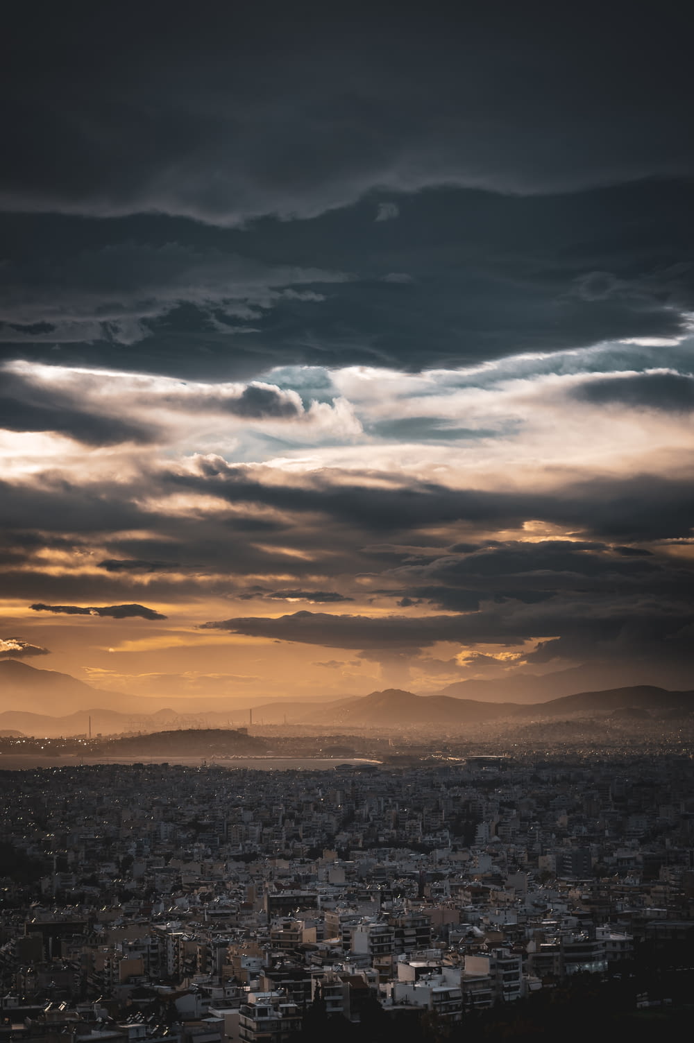 a cloudy sky over a city with mountains in the distance