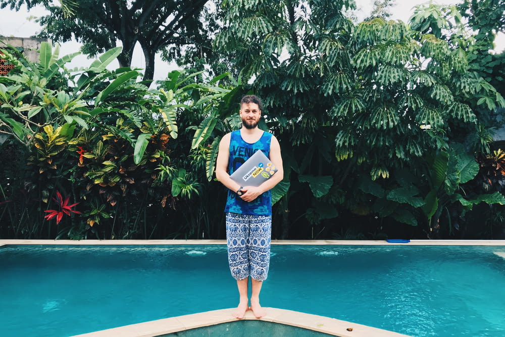 man wearing blue tank top standing on pool