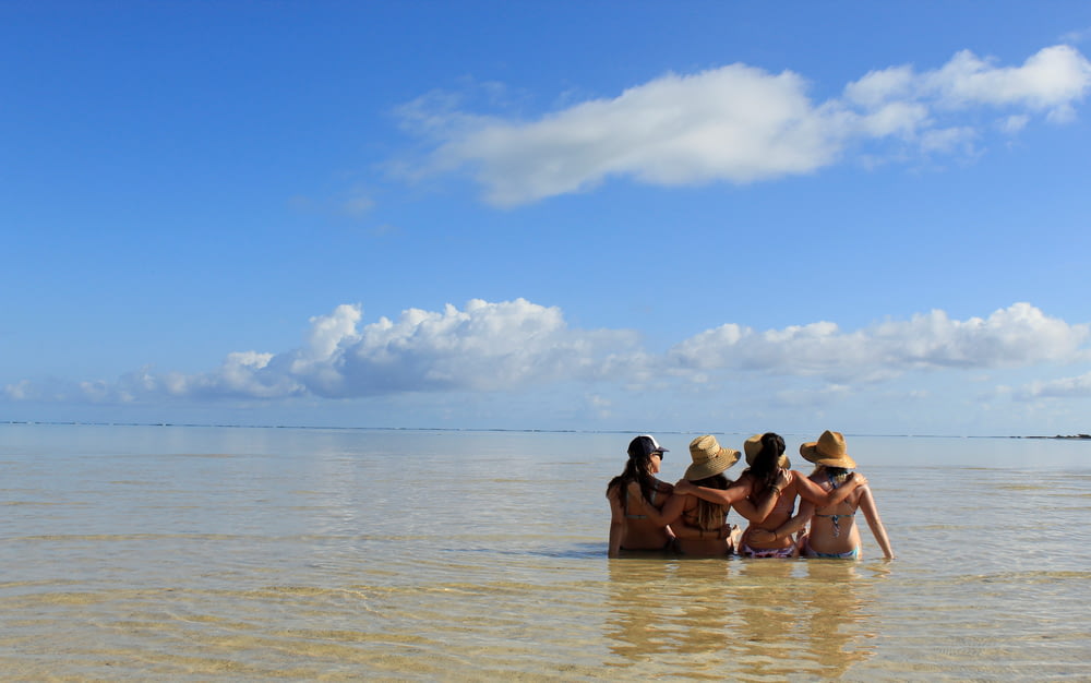 quatro mulheres sentadas no corpo d'água durante o dia