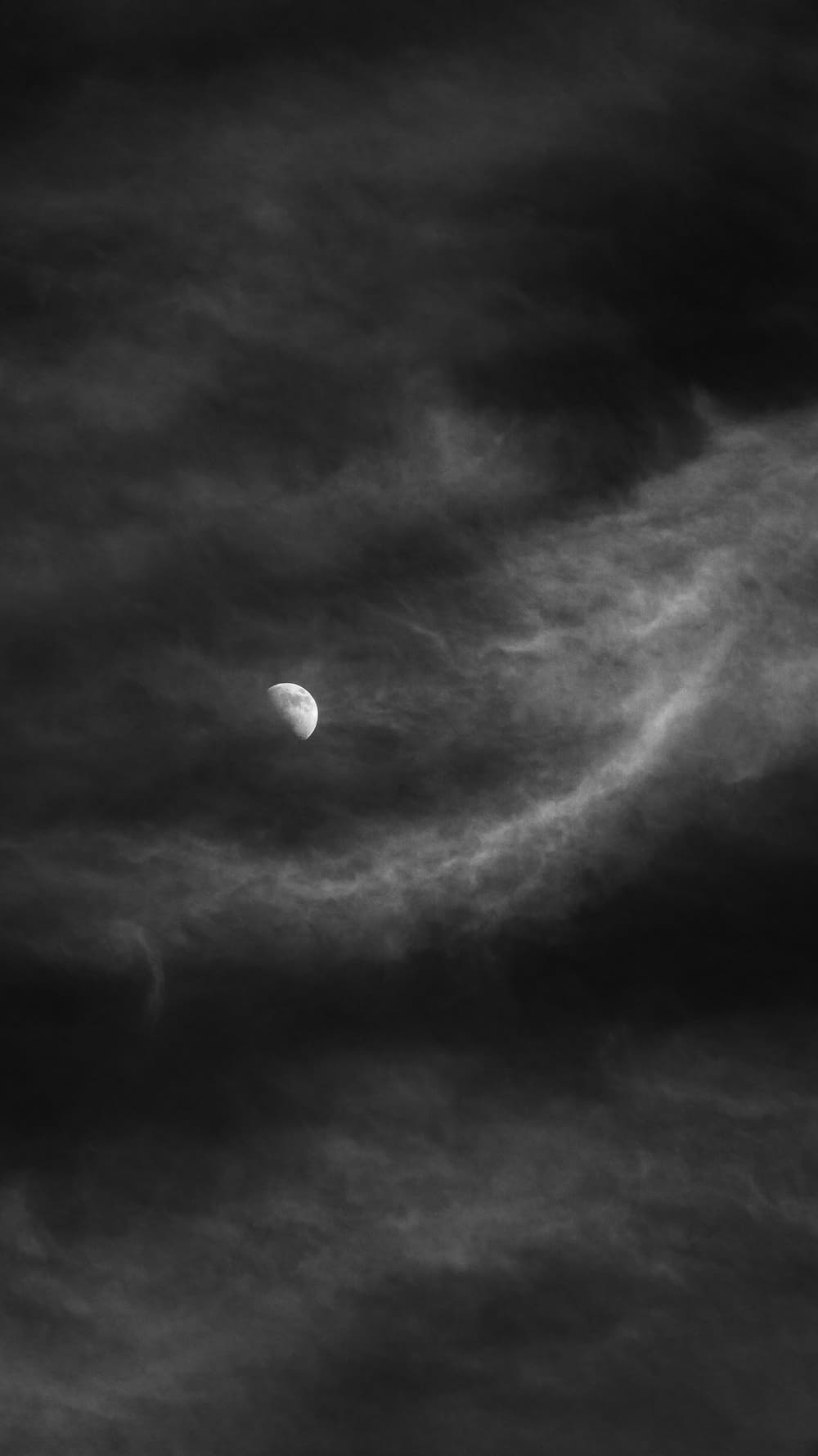 a black and white photo of the moon in a cloudy sky