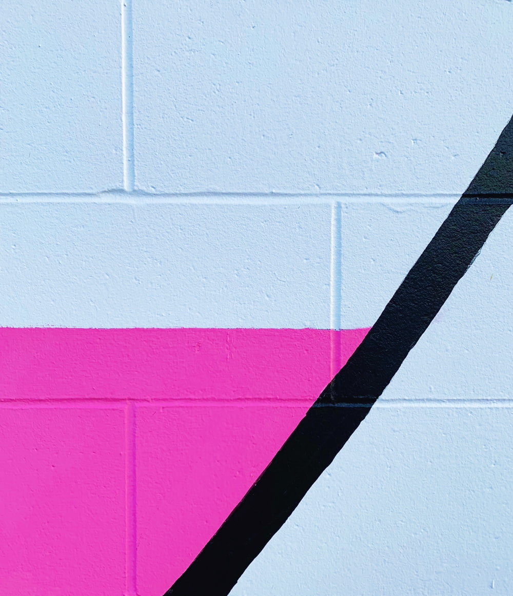 a pink and black wall with a black and white painting on it
