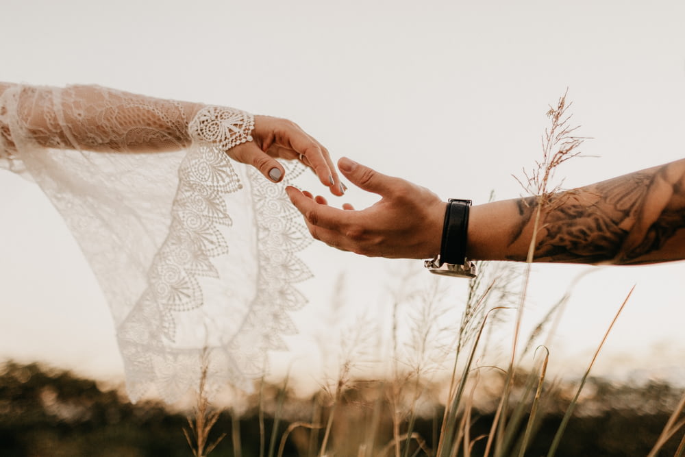 une mariée et un marié se tenant la main dans un champ
