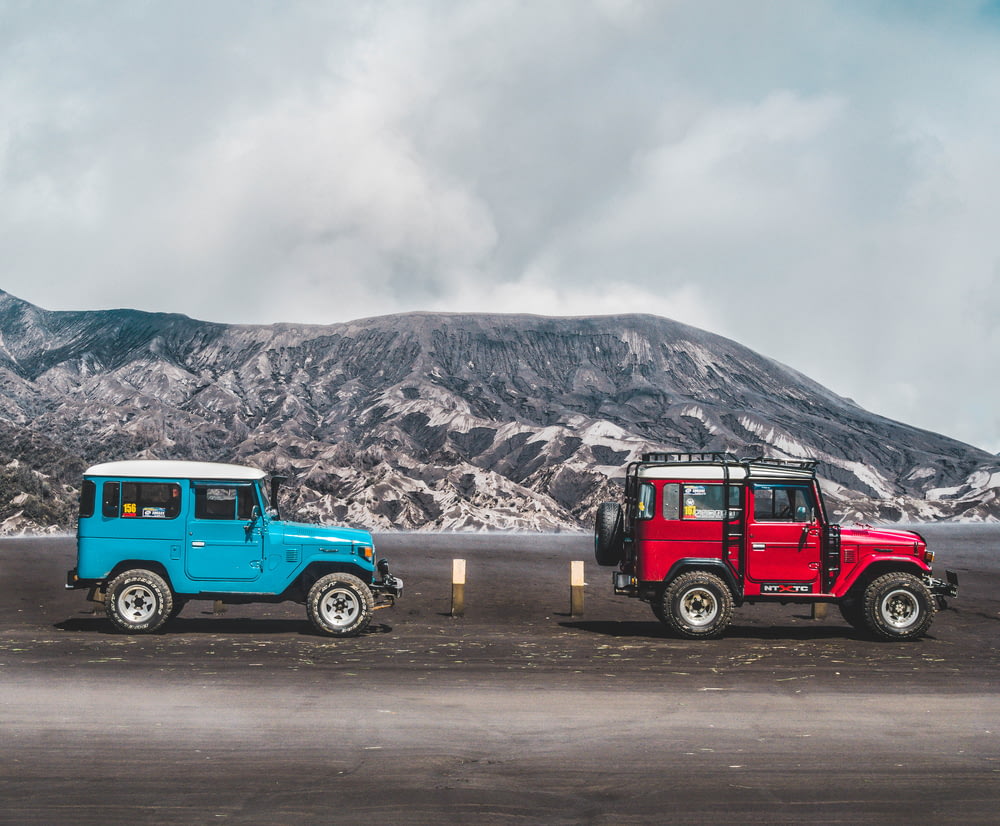 zwei blaue und rote SUVs in der Nähe des Berges