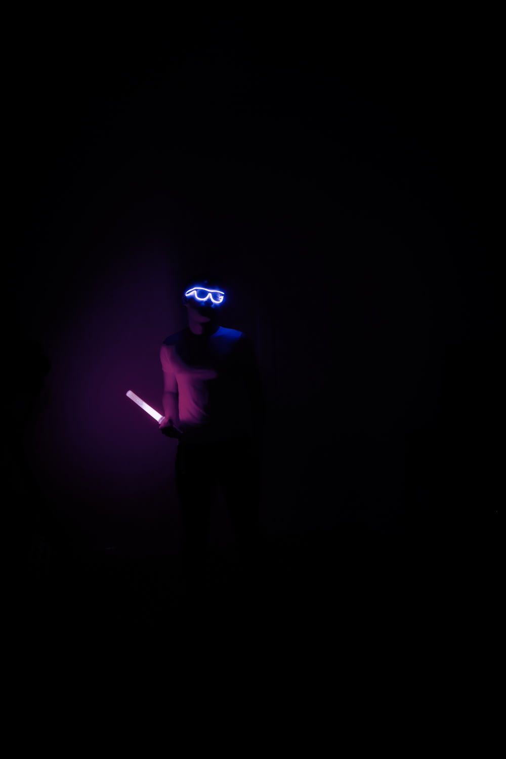 a person in a dark room holding a light saber