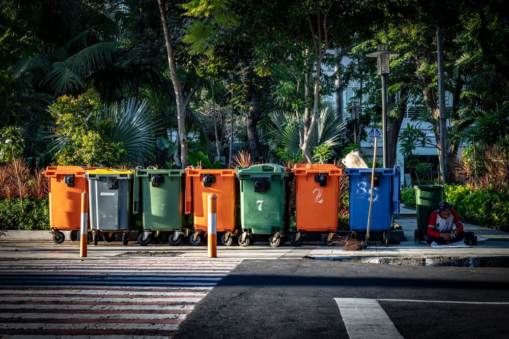 assorted-color trashbins on sidewalk during daytime