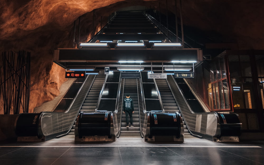 man with backpack going up escalator