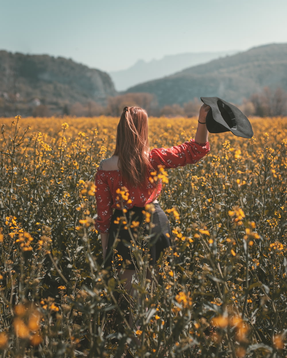 woman holding hat in flower field