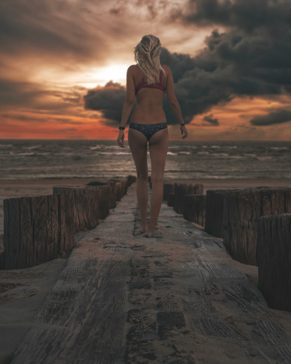 woman wearing bikini standing on wooden dock