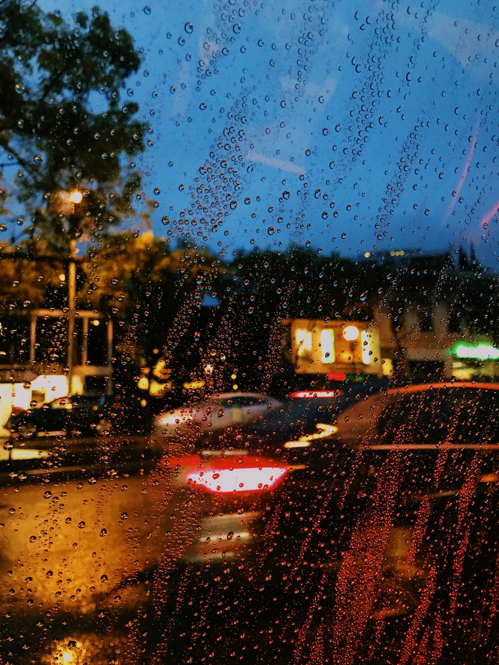 a rain covered window with cars parked on the side of the road