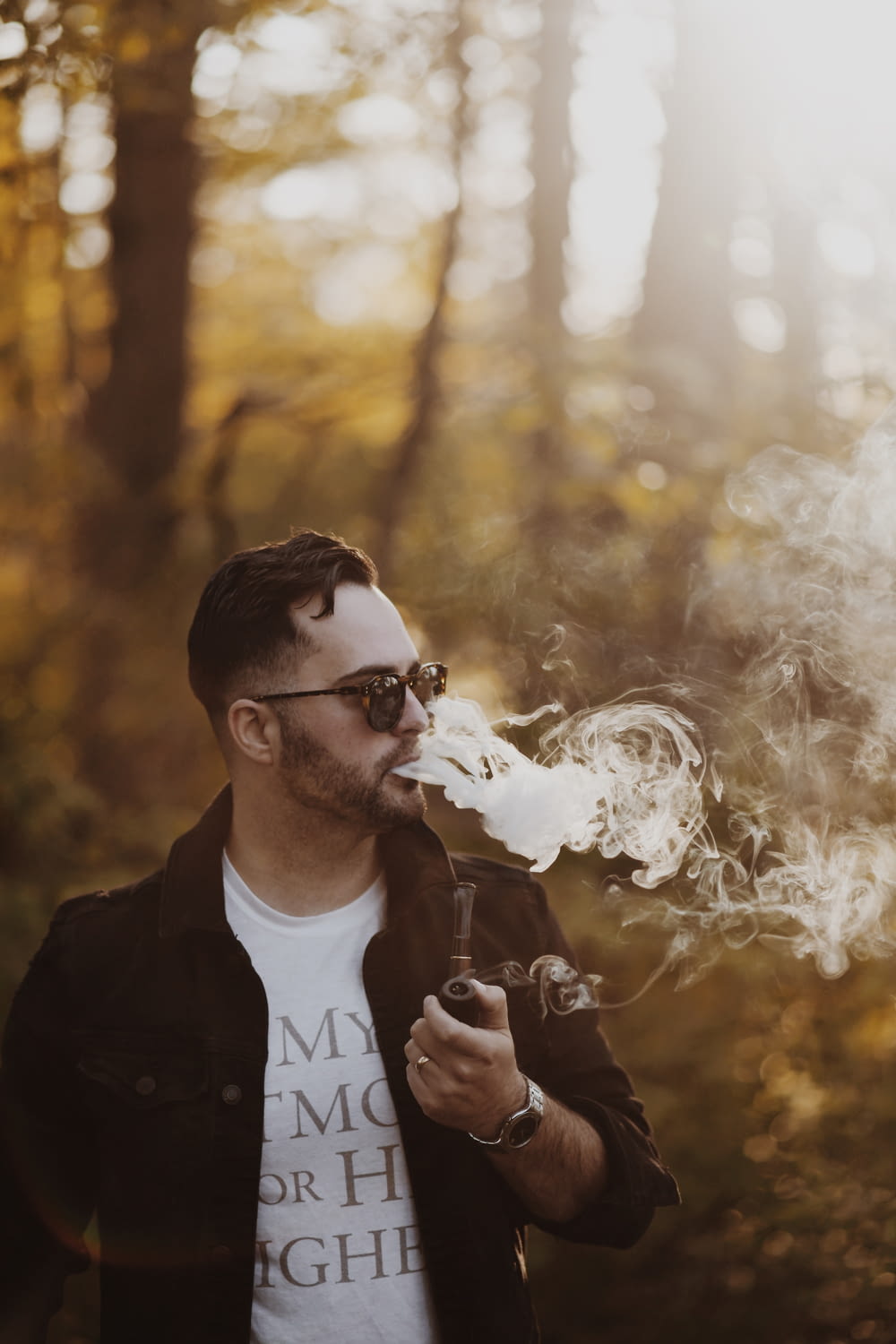 homme portant une veste noire tenant une pipe à fumer