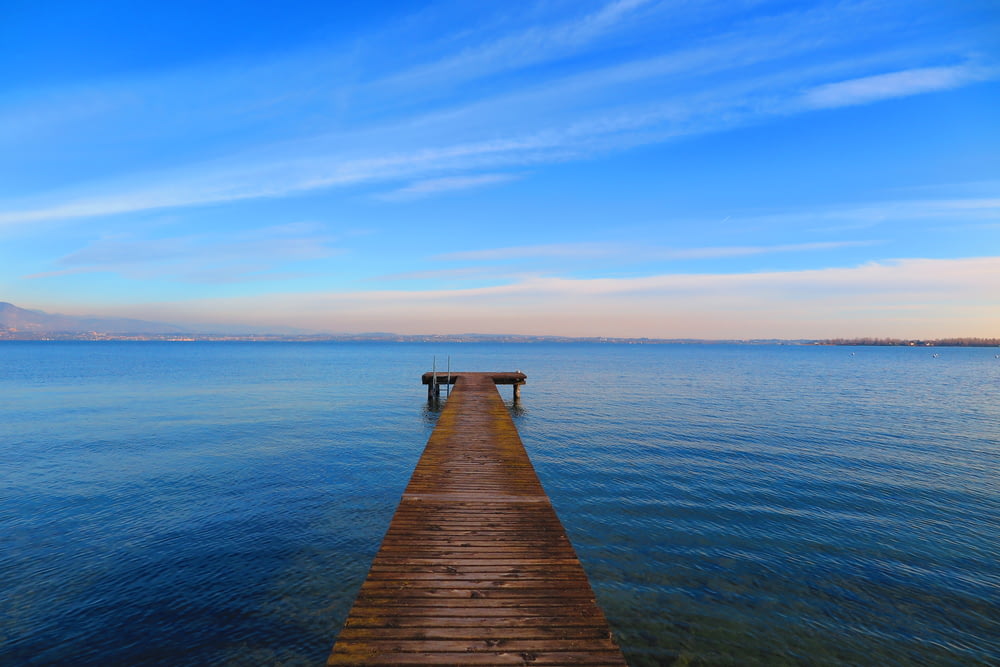 brown wooden dock on body of water under blue sky