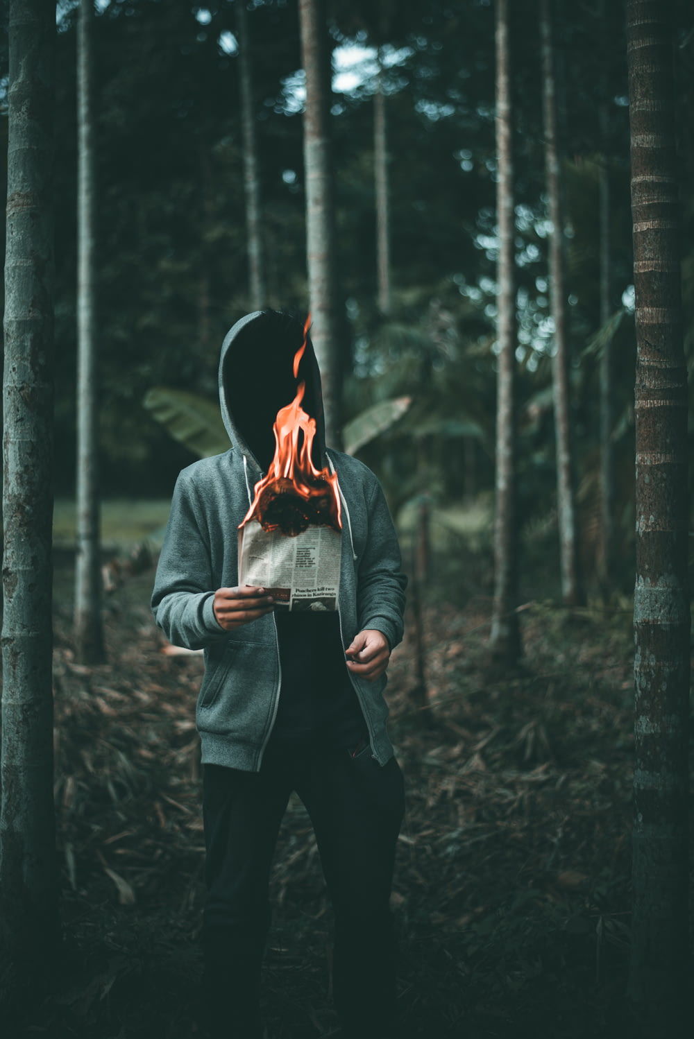 man holding burning paper near trees
