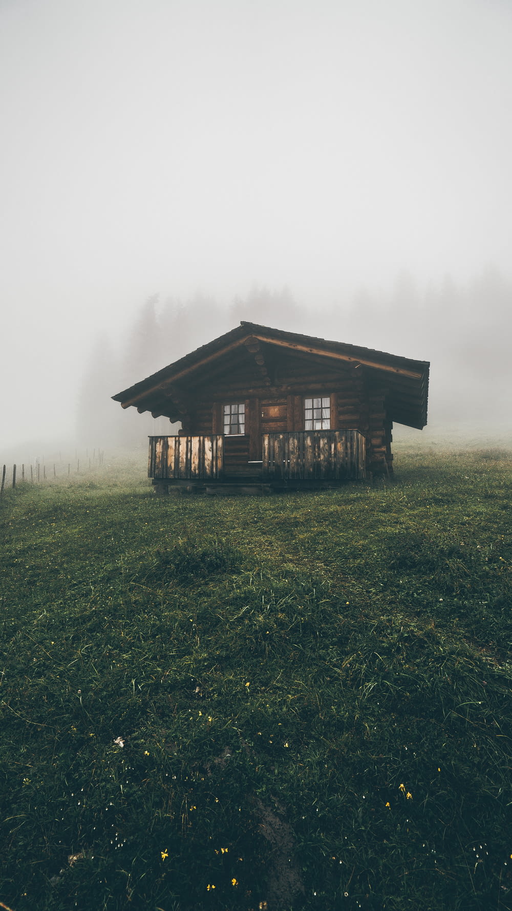 brown wooden house in a field with fog during daytime