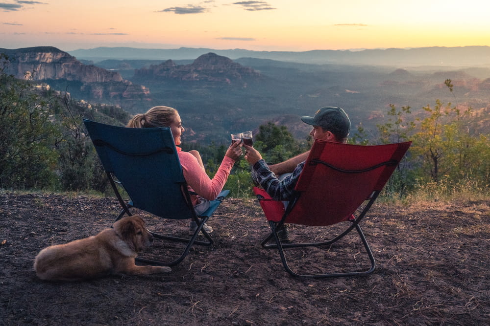 deux personnes assises sur des chaises de camping tout en regardant la montagne