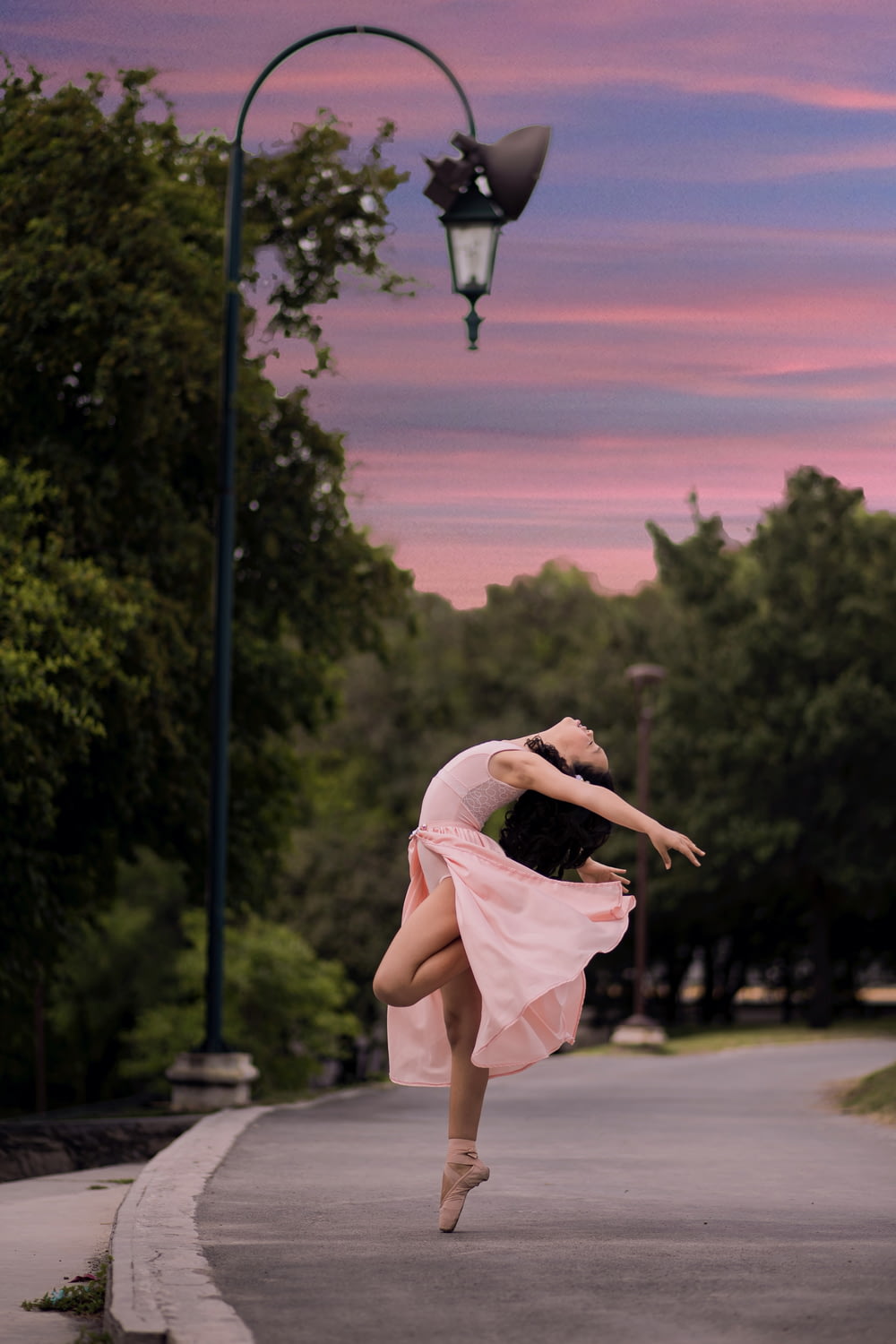 danseuse de ballet sur la route à côté d’un lampadaire