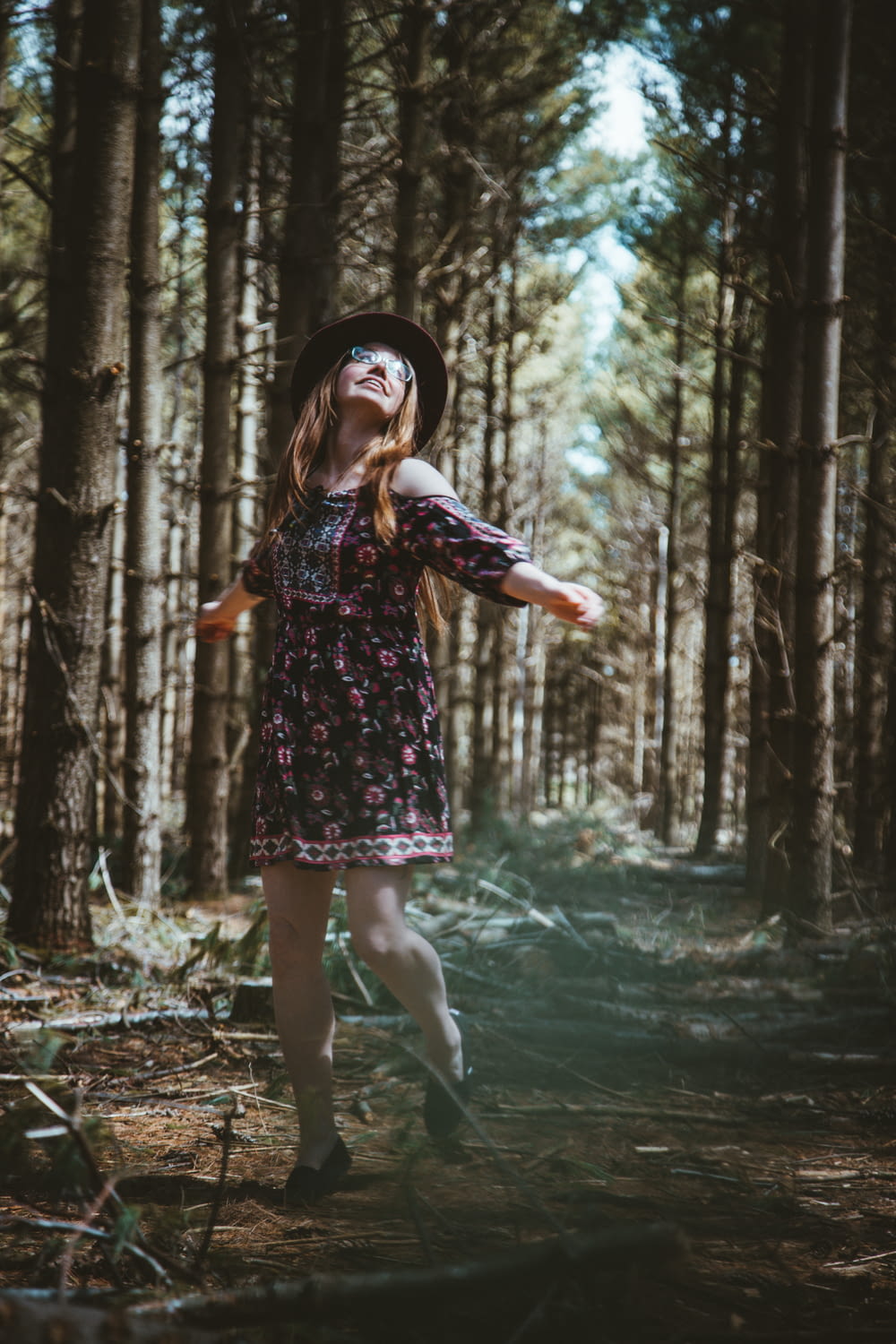 woman in multicolored floral dress standing in woods