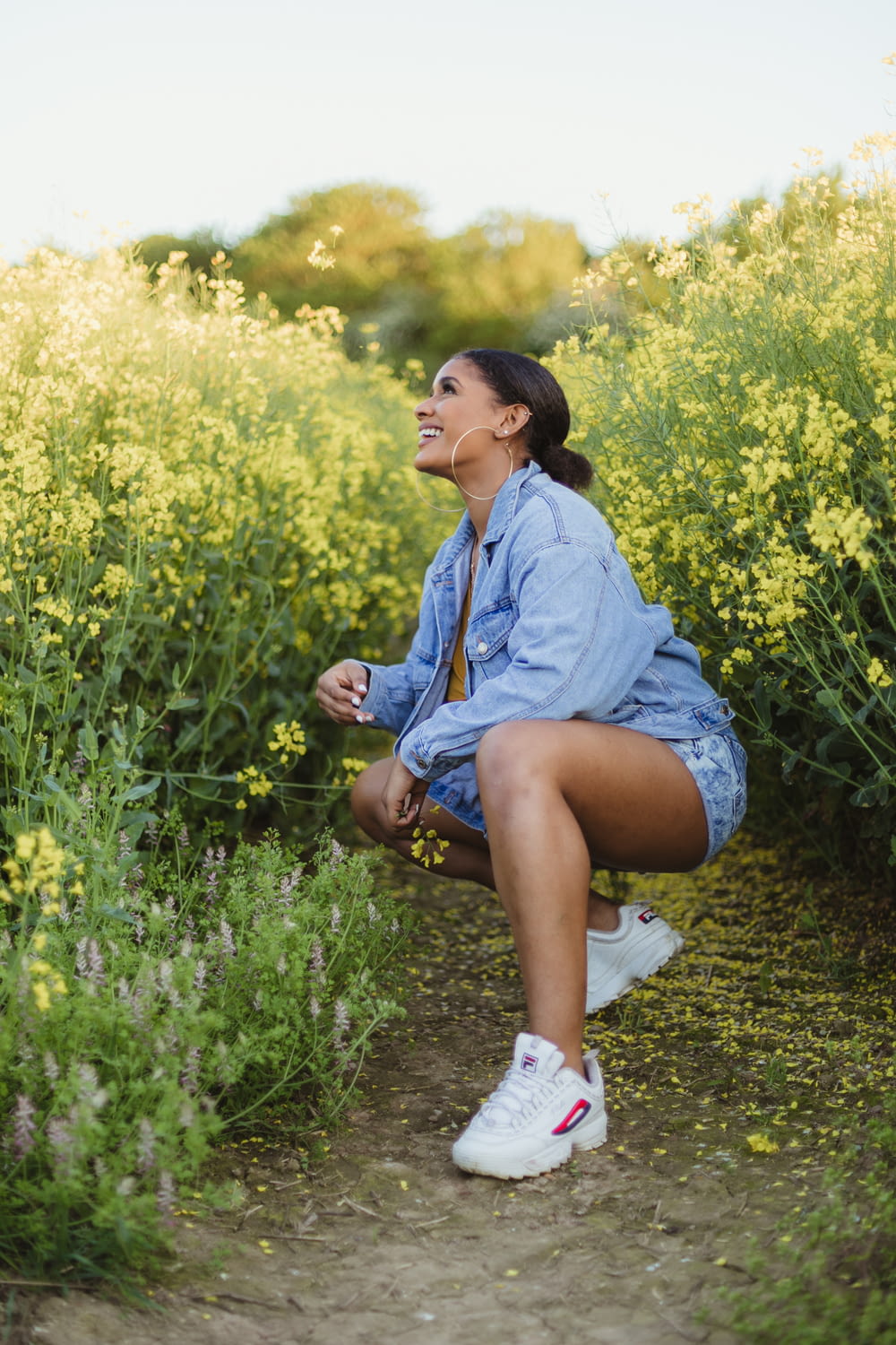 smiling woman sitting between yellow flowers