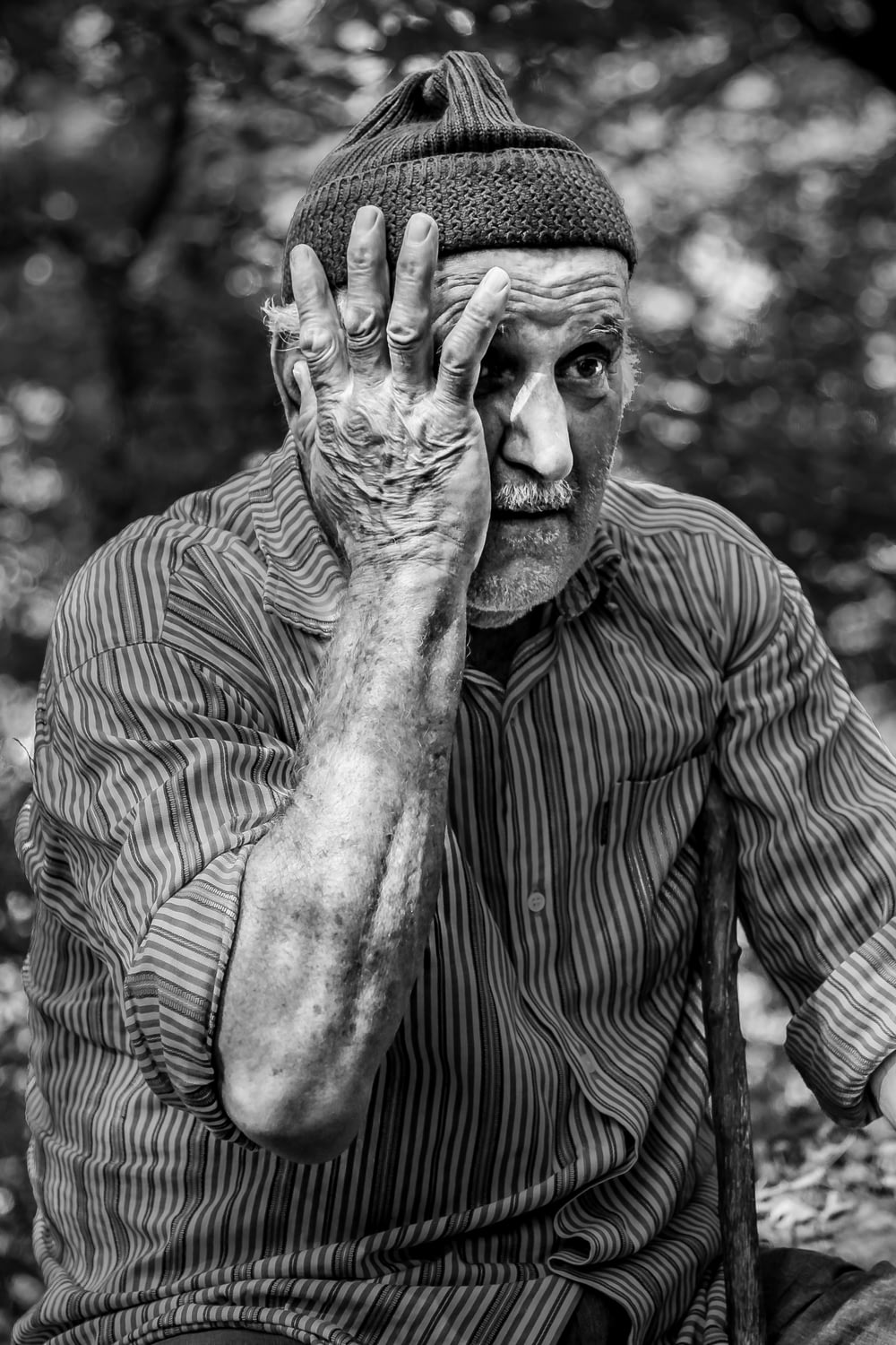 Mann im langärmeligen Nadelstreifenhemd legt Hand aufs Gesicht