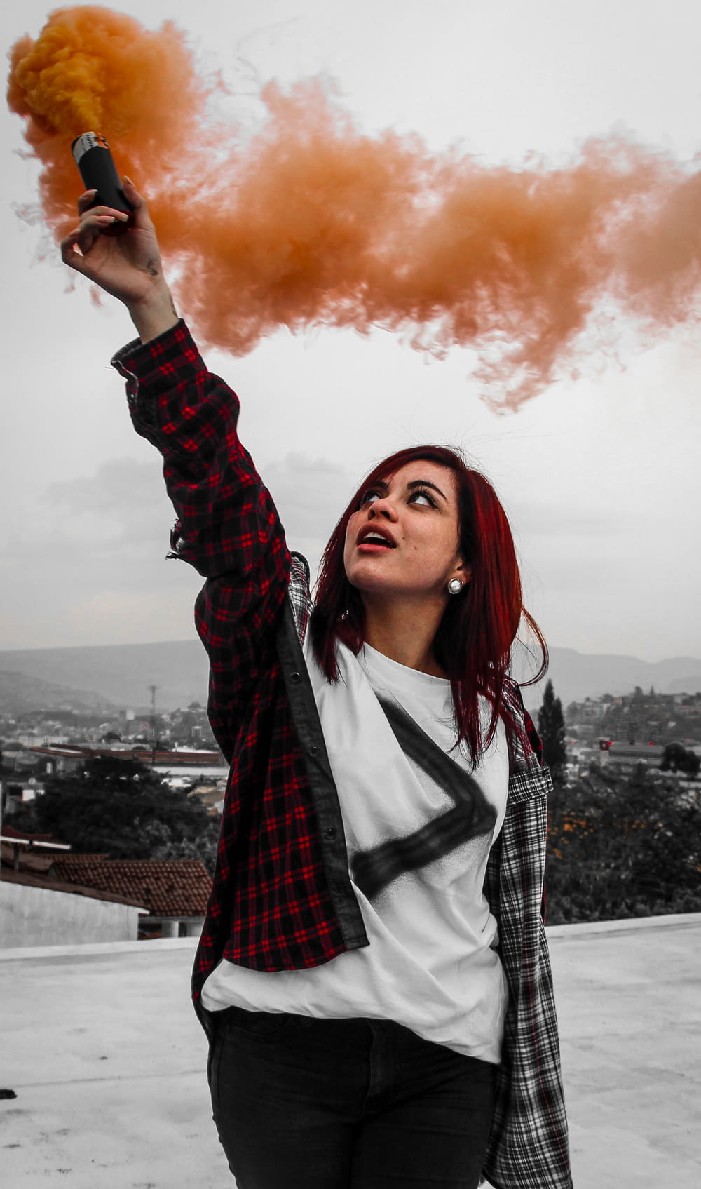 woman holding orange smoke flares at rooftop