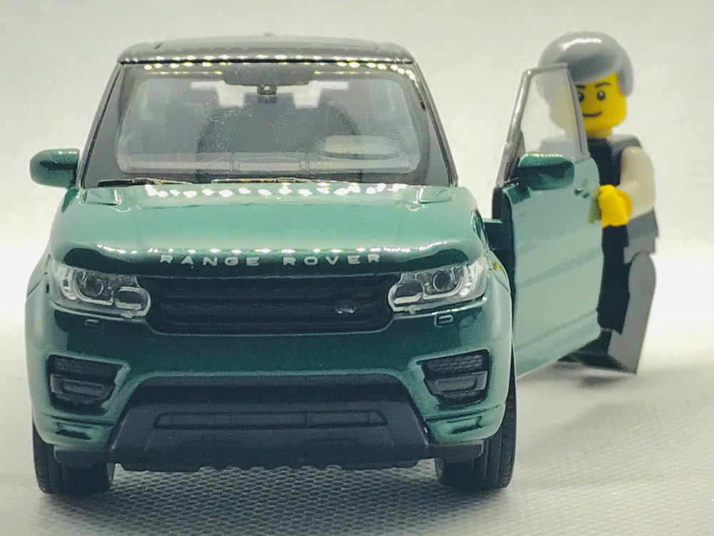 green Range Rover SUV scale model with minifig standing at open door