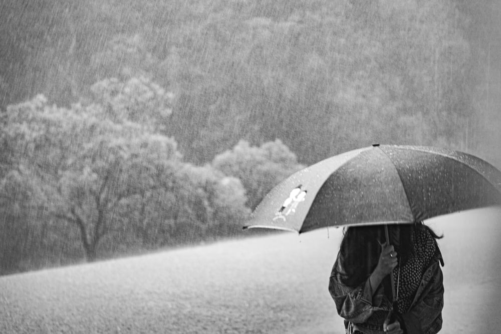 Frau unter Regenschirm bei Regen