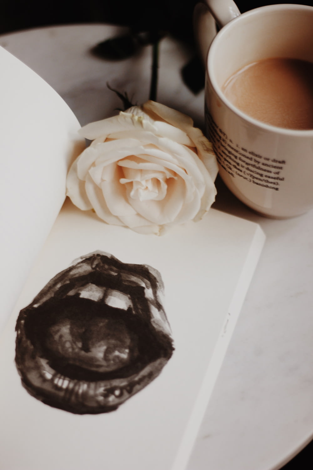 white rose flower beside mug of coffee