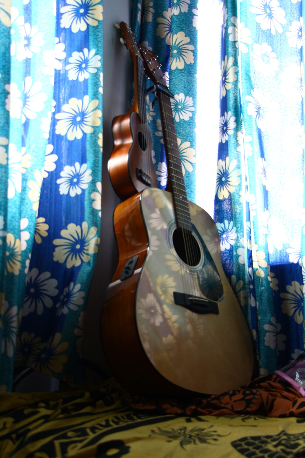 acoustic guitar beside window with curtains