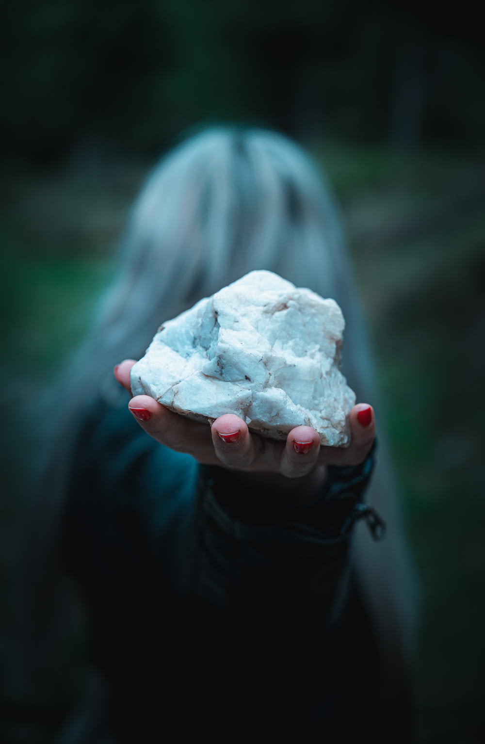 shallow focus photography of unknown person holding white stone