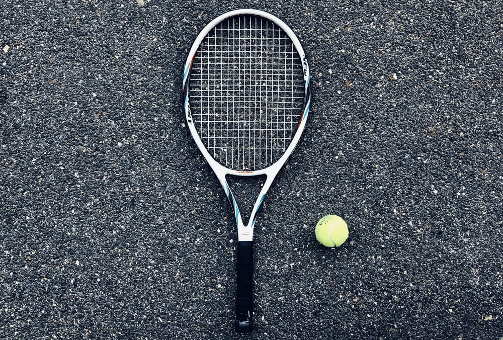 Raquette de tennis blanche et balle de tennis verte