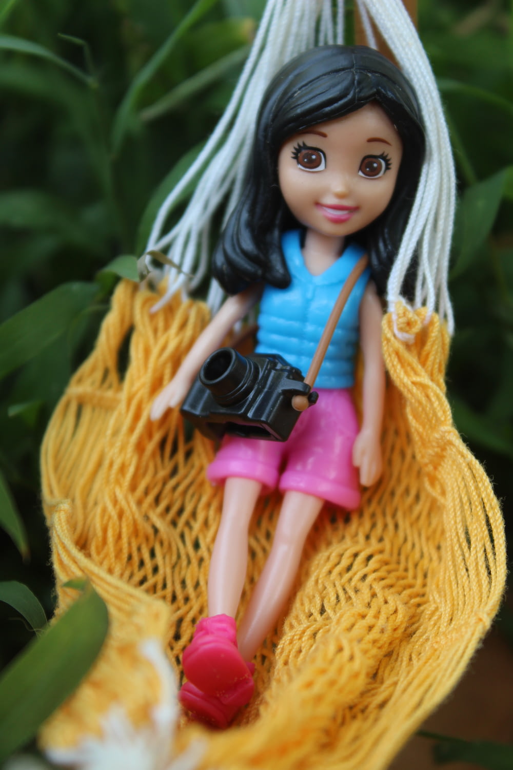 girl wearing blue tank top and shorts doll on hammock