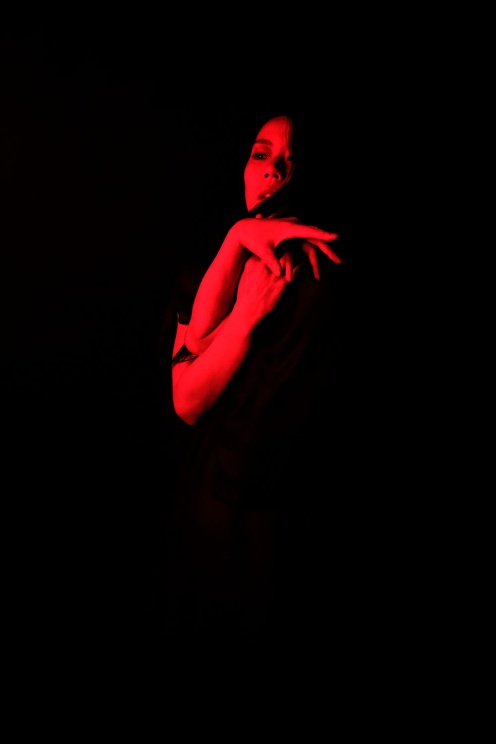 a woman standing in the dark with her arms crossed
