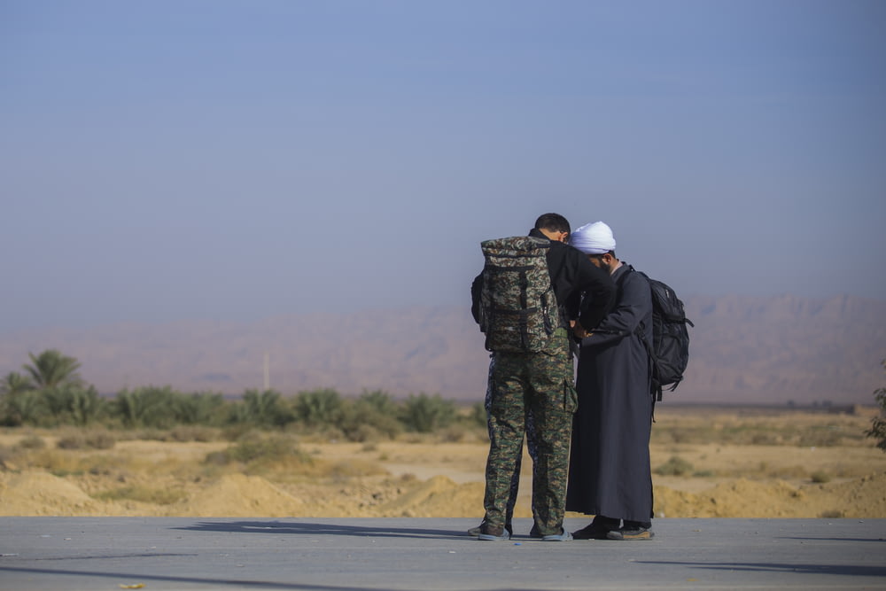 man wearing camouflage soldier uniform besides man wearing white turban