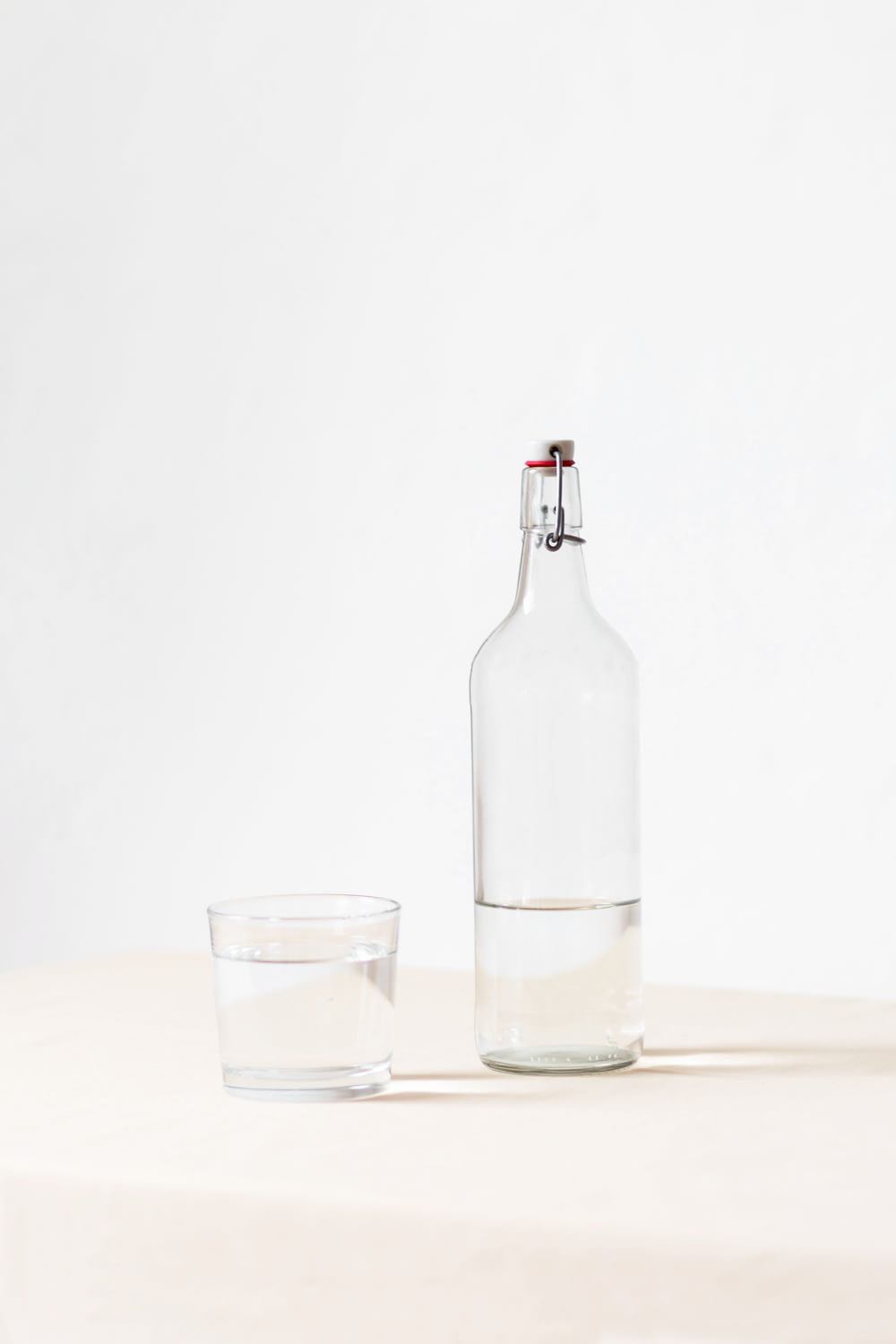 rocks glass beside half empty bottle on white surface
